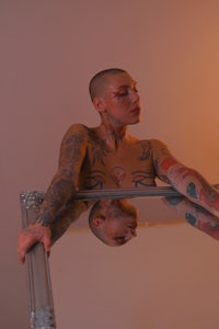 a woman with tattoos standing in front of a mirror