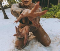 a woman in a bikini with her hands in the sand