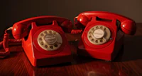 two red telephones on a wooden table